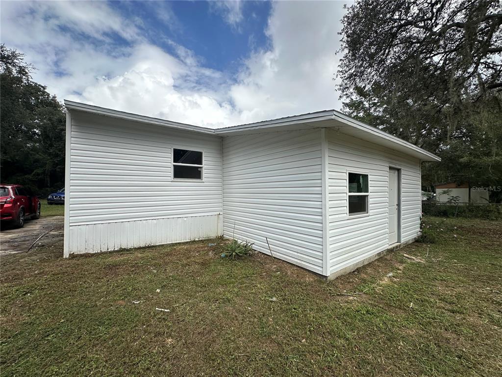The exterior of a white, vinyl-sided building with a metal roof and two windows — 17405 NE 38TH LANE ROAD, SILVER SPRINGS, FL