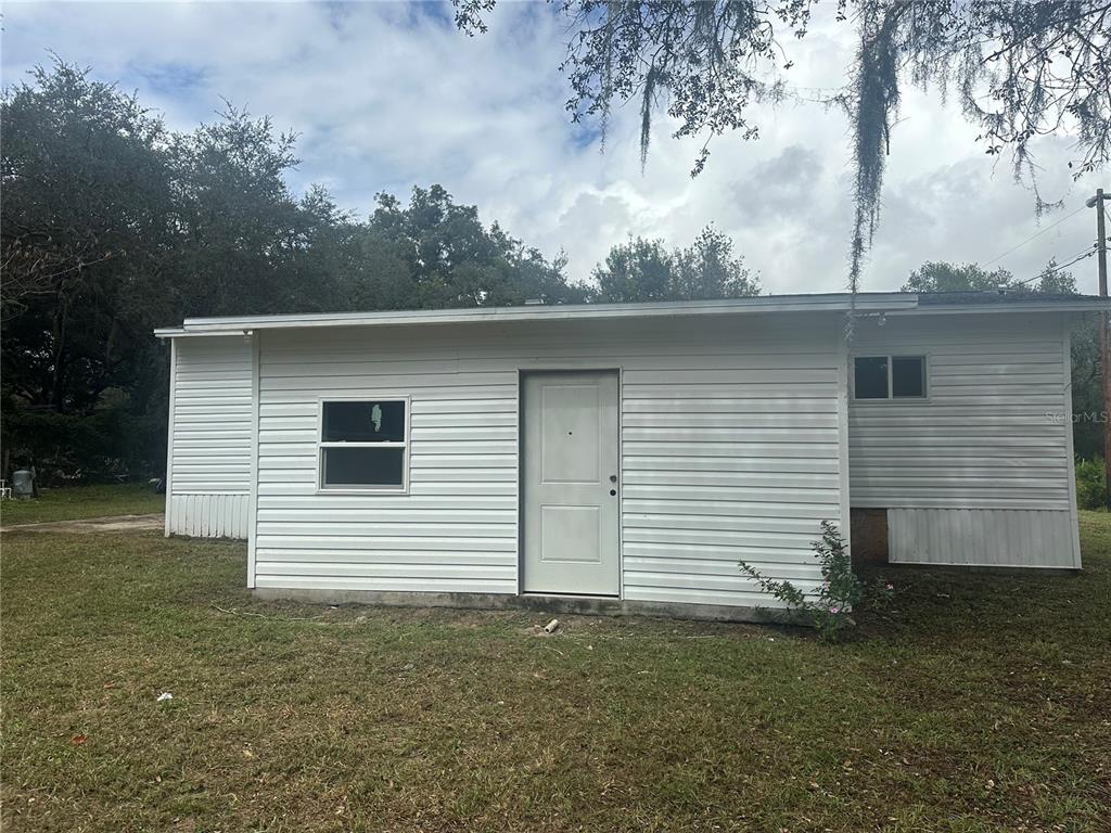 A white, single-story exterior structure with horizontal siding, a central door, and two windows — 17405 NE 38TH LANE ROAD, SILVER SPRINGS, FL