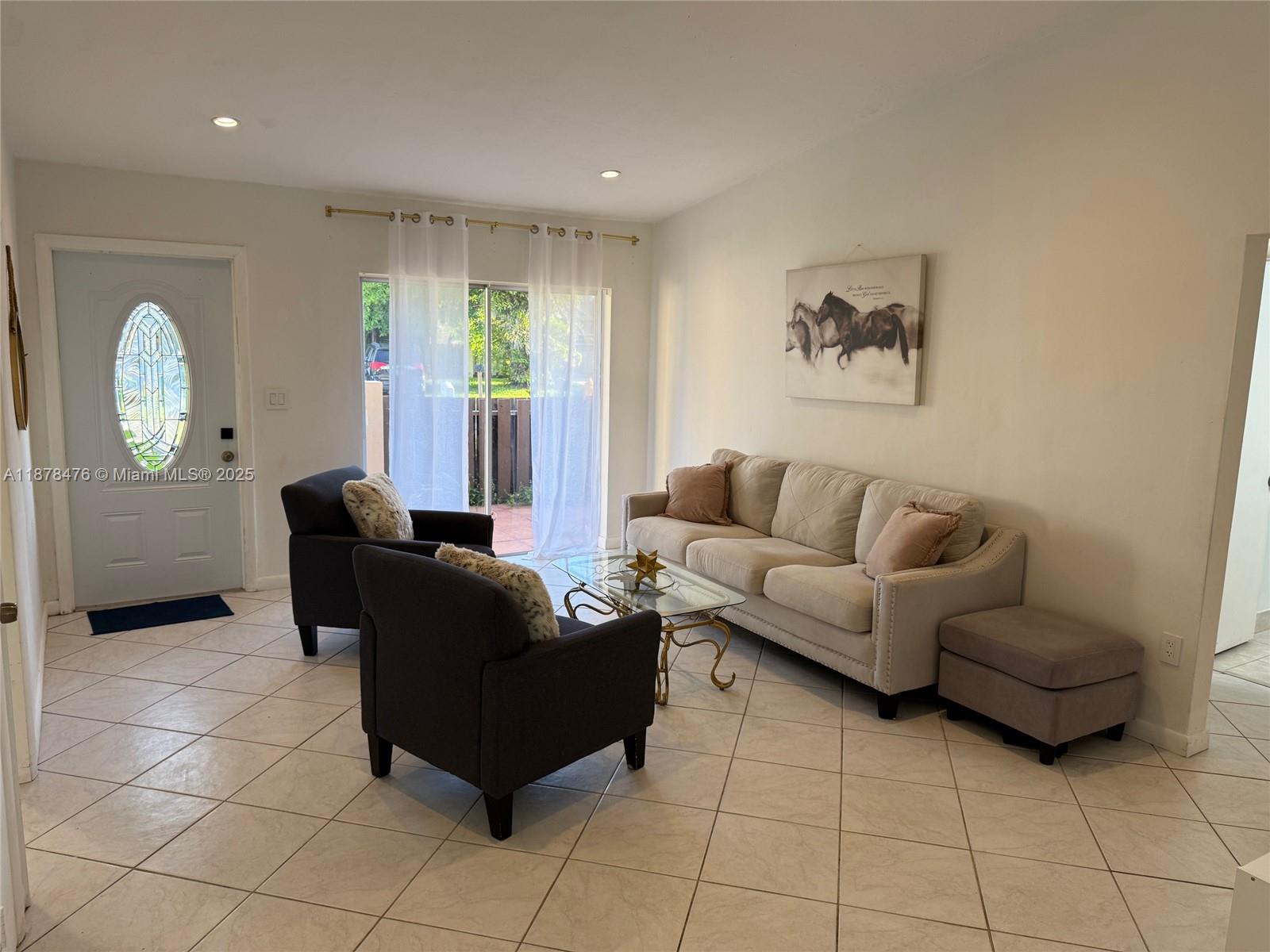 A living room features light tile flooring, a beige sofa, two dark armchairs, and sliding doors — 12413 SW 112th Ter, Miami FL 33186, MIAMI, FL