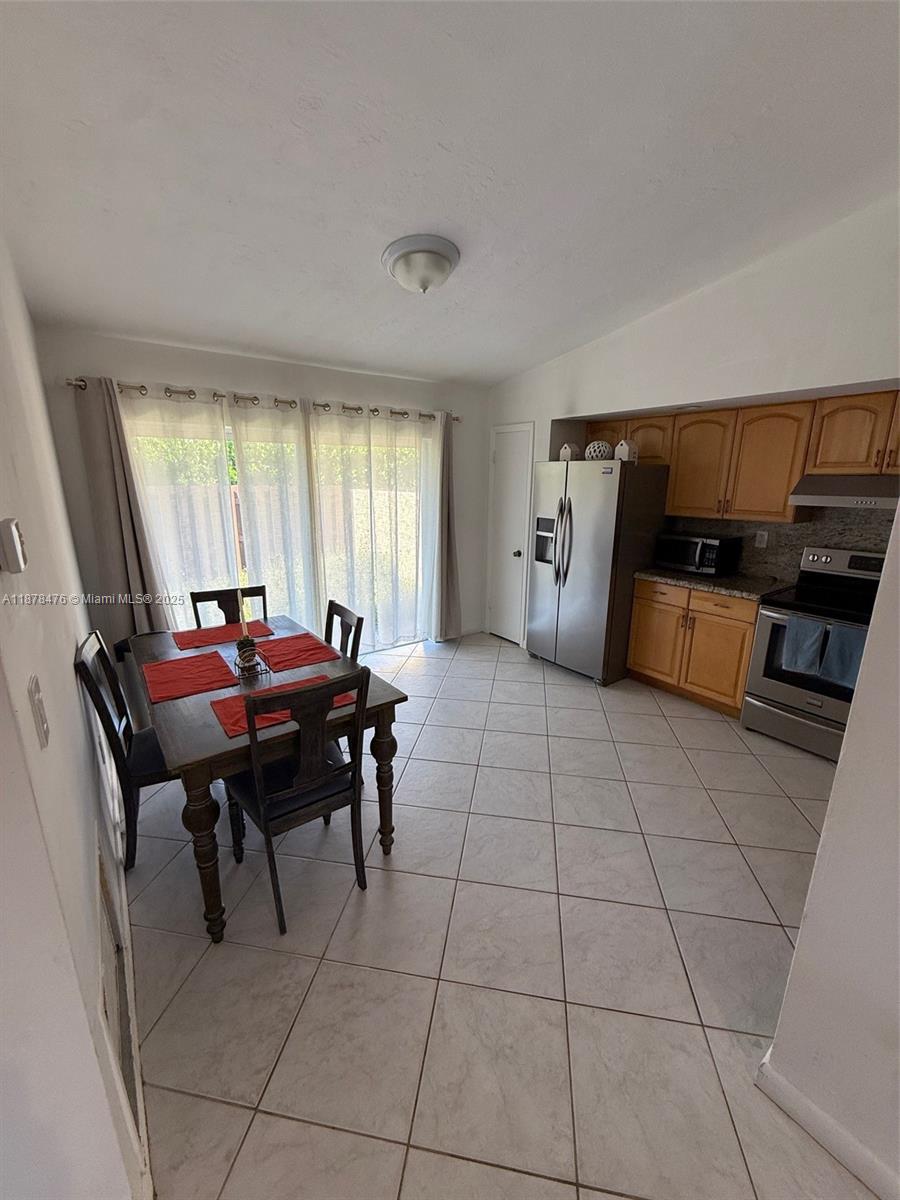 A kitchen and dining area with light tile floors, wooden cabinets, and stainless steel appliances — 12413 SW 112th Ter, Miami FL 33186, MIAMI, FL