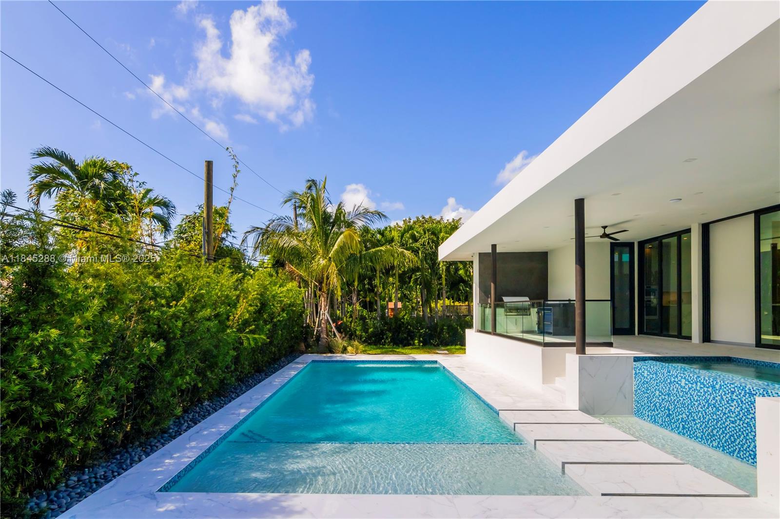 A modern house features a swimming pool with a sun shelf and a covered patio — 1248 NE 89th St, Miami FL 33138, MIAMI, FL