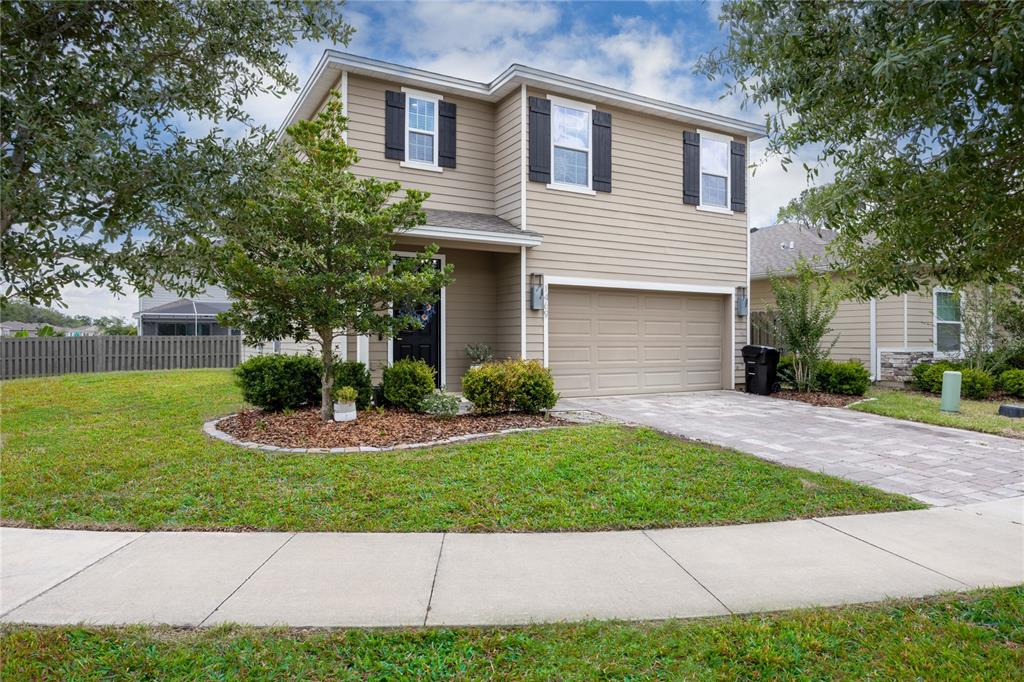 A two-story house with beige siding, a two-car garage, and a landscaped front yard — 1469 NW 136TH DRIVE, NEWBERRY, FL