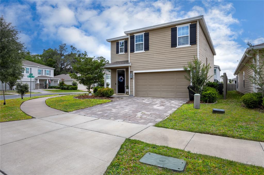 A two-story house with tan siding, a paved driveway, and a two-car garage — 1469 NW 136TH DRIVE, NEWBERRY, FL