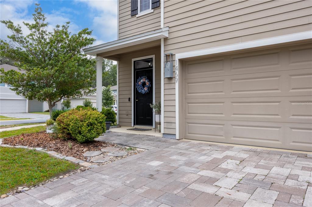 A tan house exterior features a black front door, a garage, and a paved driveway — 1469 NW 136TH DRIVE, NEWBERRY, FL
