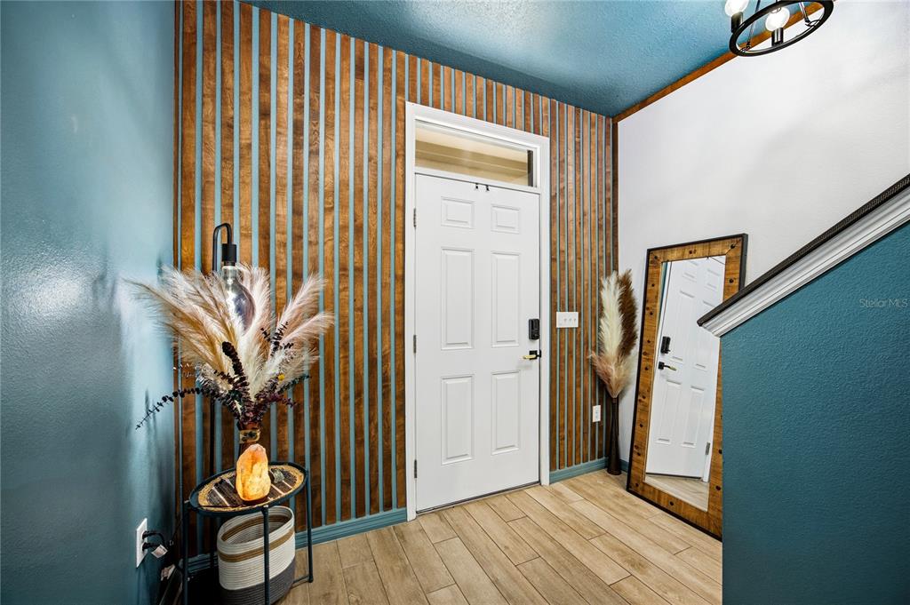 An entryway features a white door, wood slat accent wall, teal walls, and wood-look flooring — 1469 NW 136TH DRIVE, NEWBERRY, FL