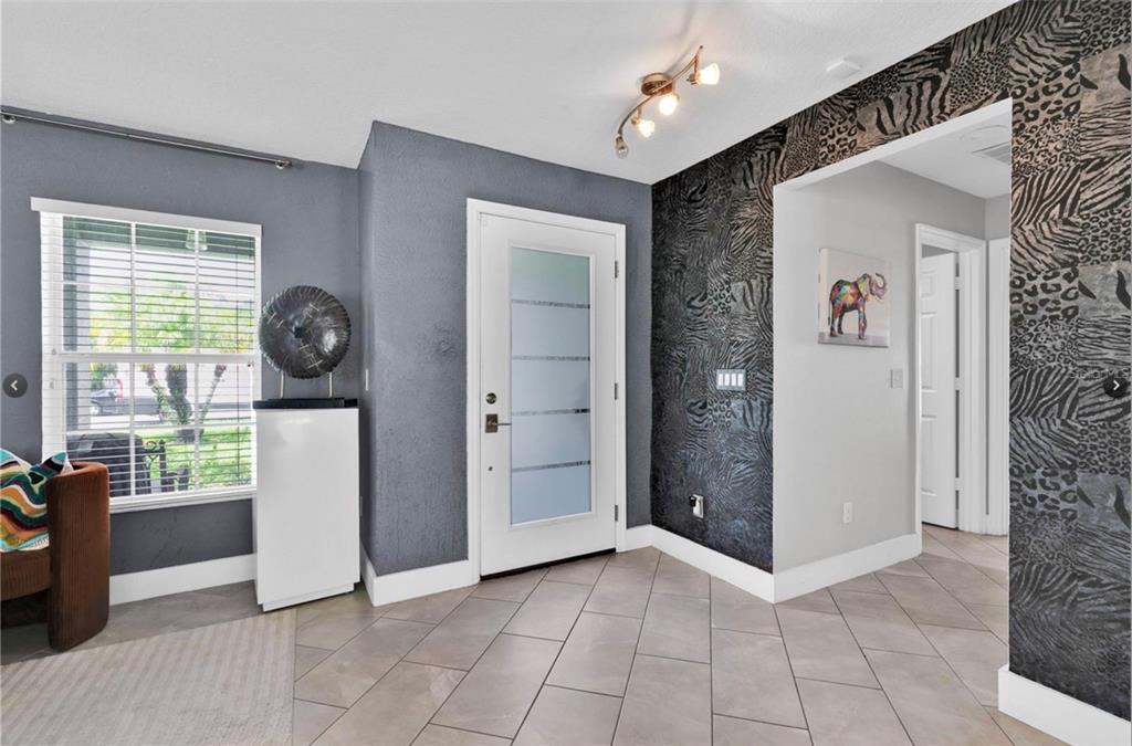 An entryway features tiled floors, a frosted glass front door, and animal print wallpaper — 1652 ALGONKIN LOOP, ORLANDO, FL
