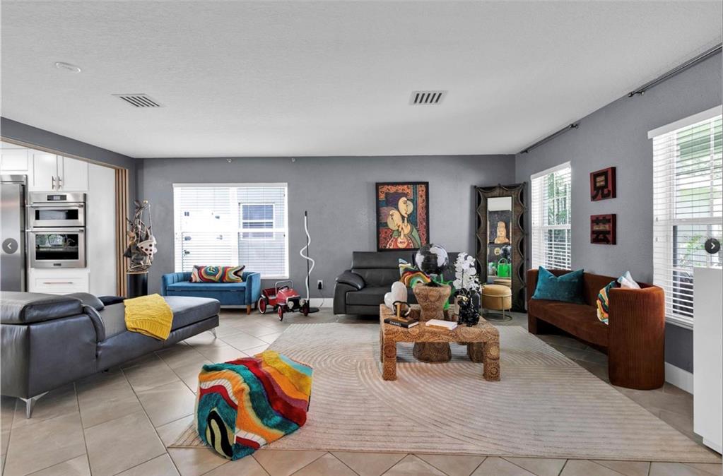 A living room features gray walls, tile flooring, a textured rug, and eclectic furniture — 1652 ALGONKIN LOOP, ORLANDO, FL