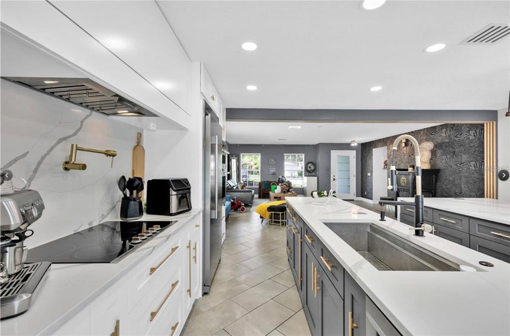 A modern kitchen features white cabinets, a gray island with a sink, and tile flooring — 1652 ALGONKIN LOOP, ORLANDO, FL