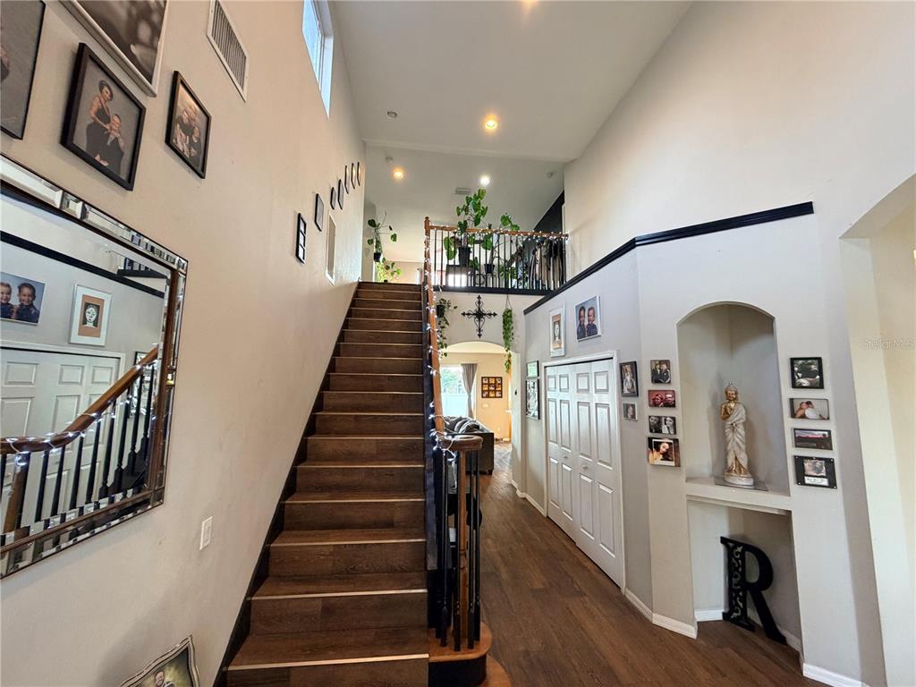 A foyer features a wooden staircase, a lofted landing, and a recessed wall niche — 4165 COPPER HILL DRIVE, SPRING HILL, FL