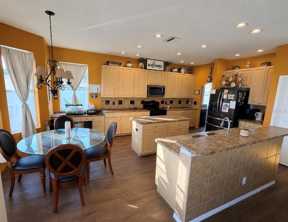 A kitchen with light wood cabinets, a center island, and a glass-topped dining table — 4165 COPPER HILL DRIVE, SPRING HILL, FL