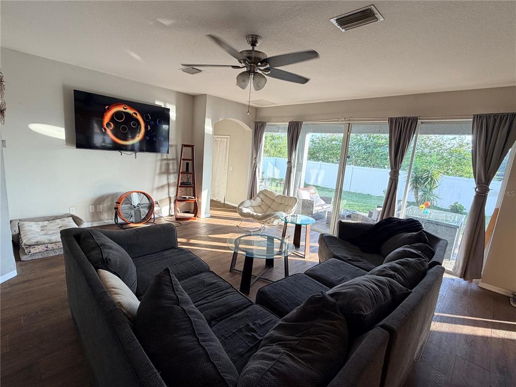 A living room features a large sectional sofa, a wall-mounted television, and sliding glass doors — 4165 COPPER HILL DRIVE, SPRING HILL, FL