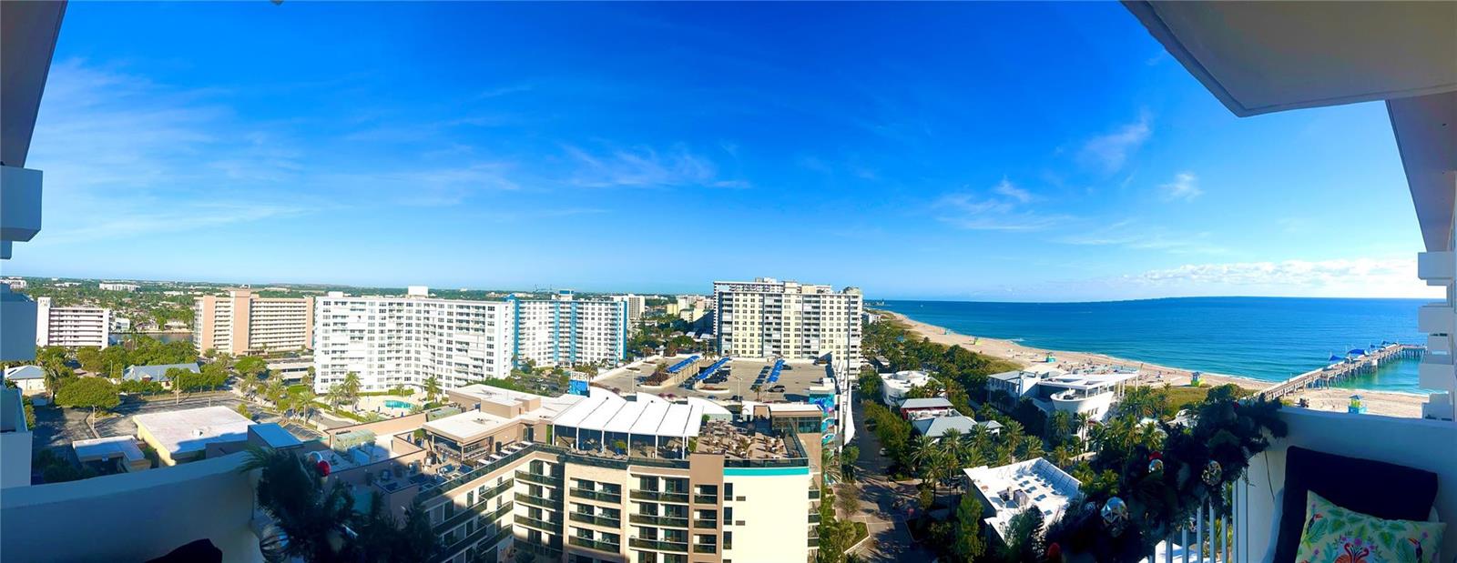 A high-angle panoramic view from a balcony overlooking a beach, ocean, and coastal city buildings — 133 N Pompano Beach Boulevard # 1506, Pompano Beach FL 33062, POMPANO BEACH, FL