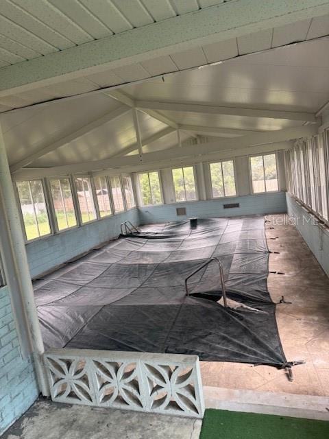 An indoor swimming pool is covered by a black tarp inside a screened-in patio area — 1921 GLENWOOD ROAD, DELAND, FL