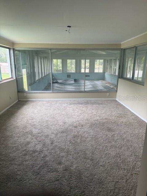 A carpeted room features a large glass-enclosed sunroom with a pool visible through the windows — 1921 GLENWOOD ROAD, DELAND, FL