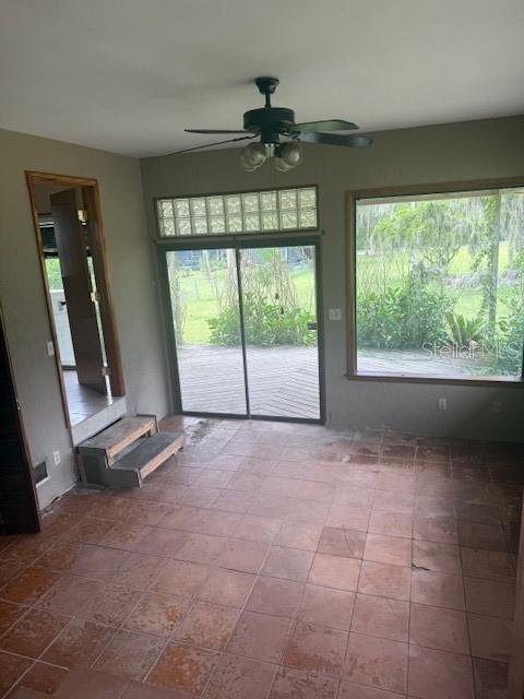 A room with terracotta tile flooring, a ceiling fan, sliding glass doors, and a large window — 1921 GLENWOOD ROAD, DELAND, FL