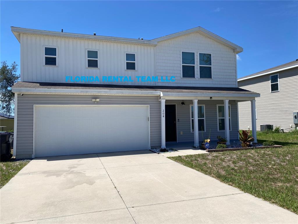 A two-story house with light gray siding, a white garage door, and a concrete driveway — 204 GLADIOLA COURT, KISSIMMEE, FL