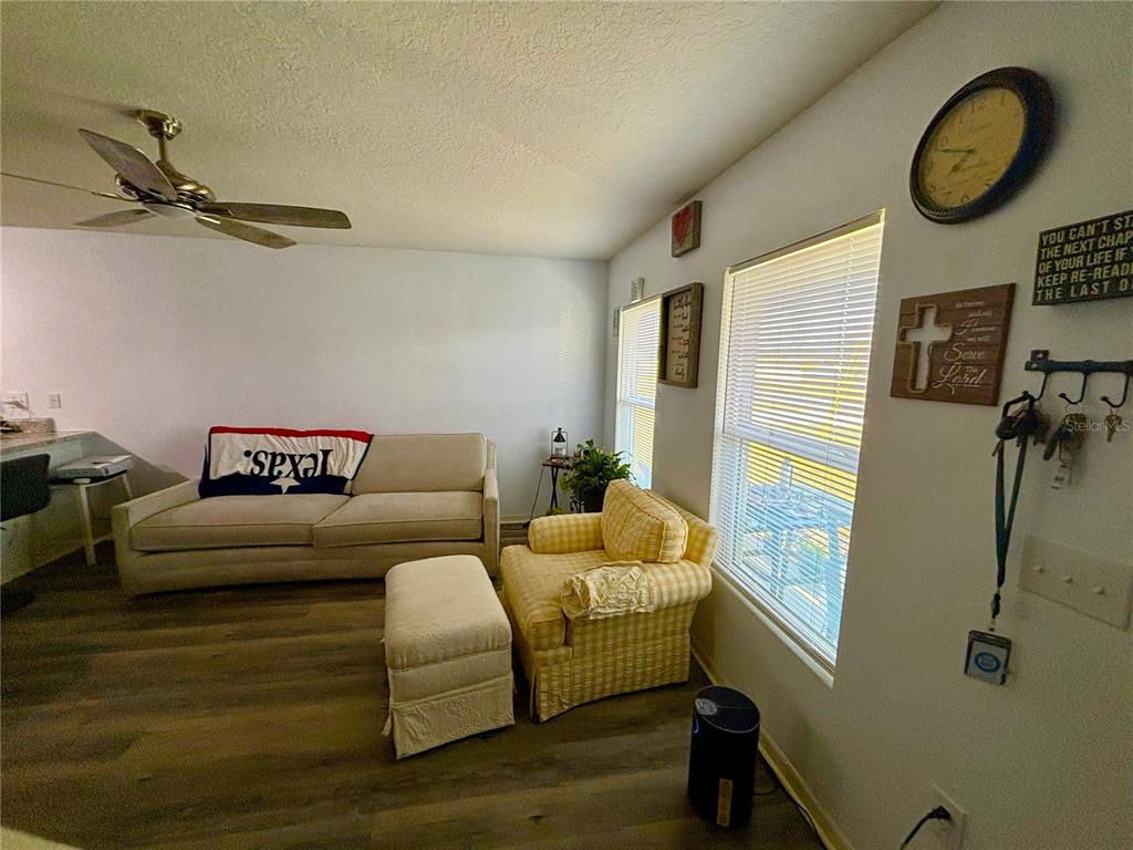 A living room features a beige sofa, a yellow armchair with an ottoman, and wood-look flooring — 204 GLADIOLA COURT, KISSIMMEE, FL