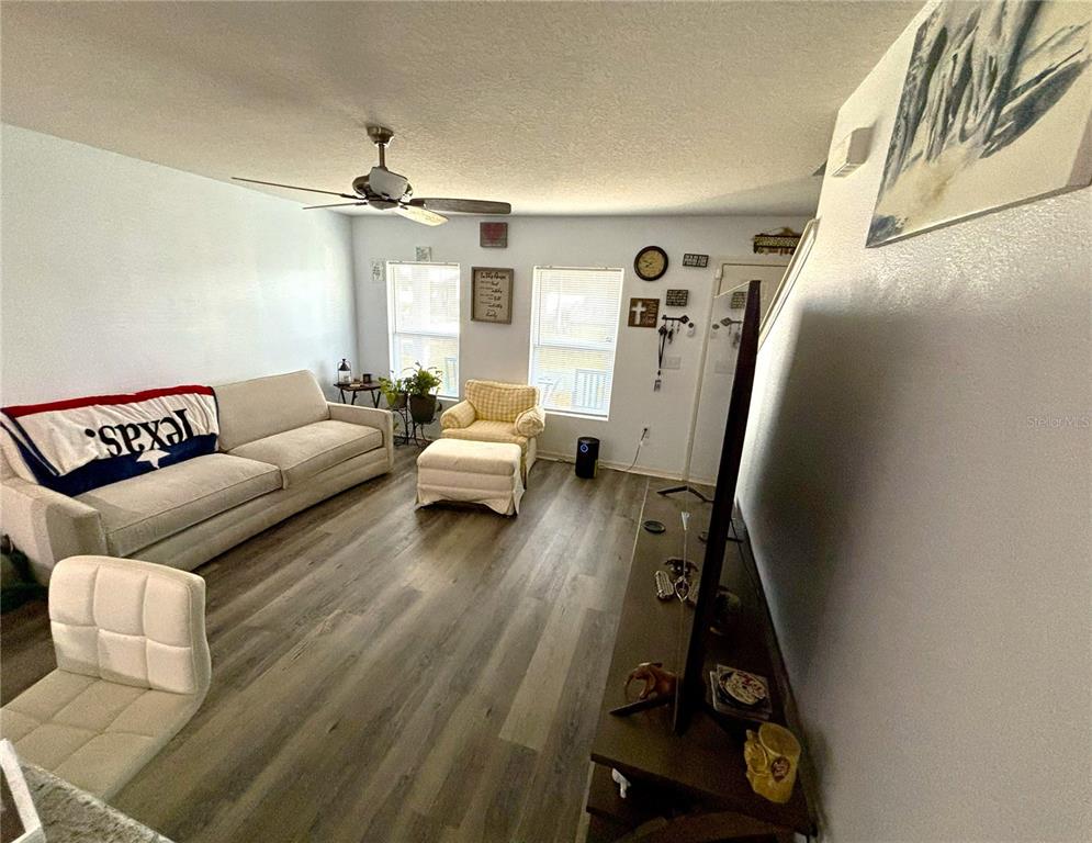 A living room features light wood-look flooring, a beige sofa, and a ceiling fan — 204 GLADIOLA COURT, KISSIMMEE, FL