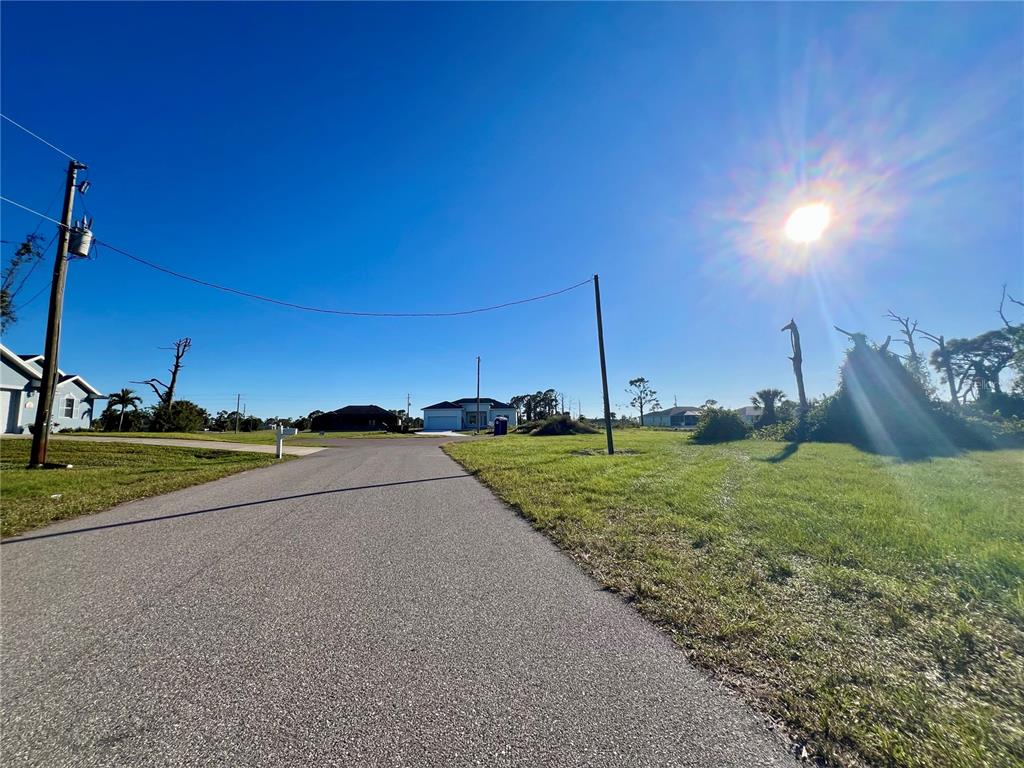 A paved road leads toward a residential house under a bright, sunny sky — 8 PENNANT PLACE, PLACIDA, FL