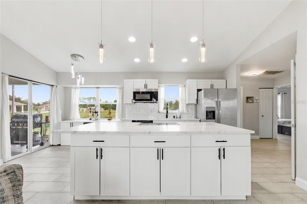 A modern kitchen features a large white island, white cabinetry, and stainless steel appliances — 12123 MALLORCA AVENUE, NORTH PORT, FL