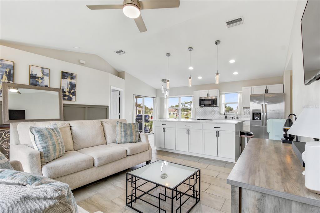 A bright open-concept living room and kitchen featuring a white island and neutral furniture — 12123 MALLORCA AVENUE, NORTH PORT, FL