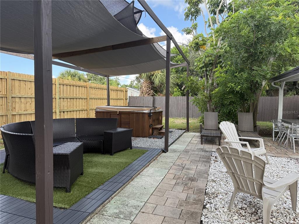 A backyard patio features a pergola, a hot tub, wicker furniture, and paved walkways — 907 FRUITLAND AVENUE, BRADENTON, FL