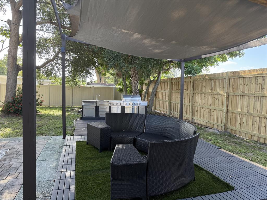 An outdoor patio features a curved wicker sofa, artificial turf, and a stainless steel grill — 907 FRUITLAND AVENUE, BRADENTON, FL