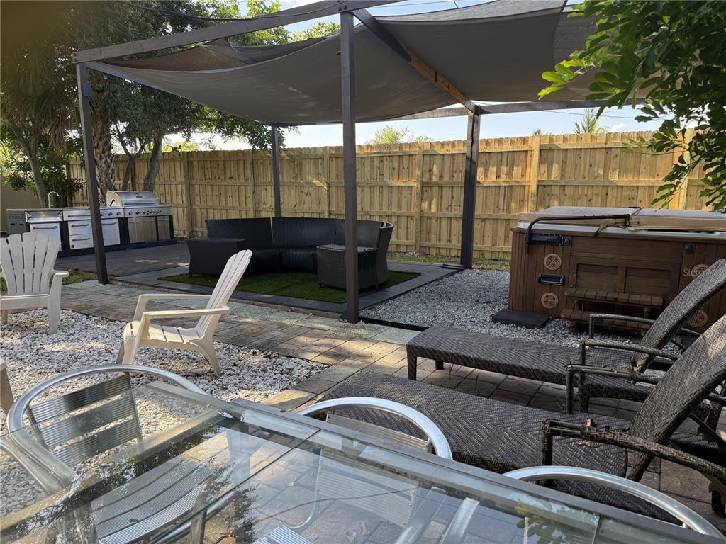 A backyard patio features a pergola, hot tub, outdoor kitchen, and various seating areas — 907 FRUITLAND AVENUE, BRADENTON, FL