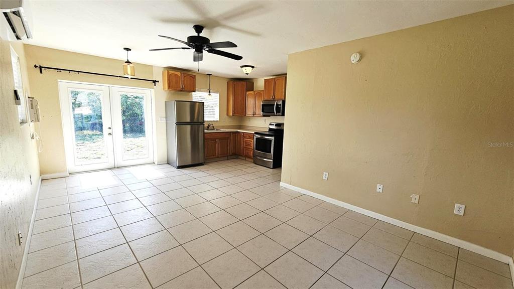 A kitchen and living area with tile floors, wooden cabinets, and glass patio doors — 865 PALM AVENUE UNIT A, ENGLEWOOD, FL