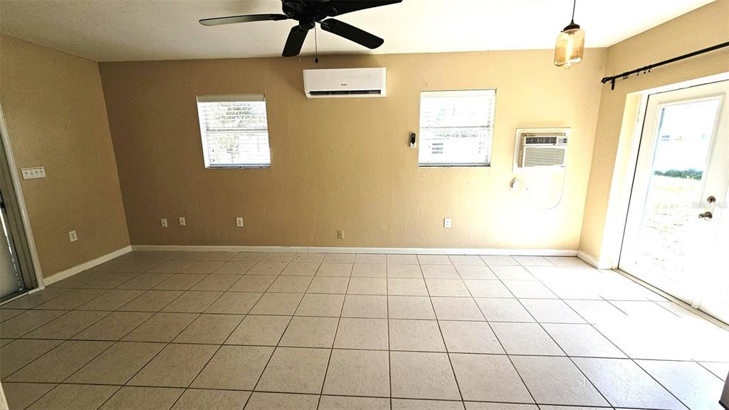 An interior room features beige walls, light-colored tile flooring, a ceiling fan, and two windows — 865 PALM AVENUE UNIT A, ENGLEWOOD, FL