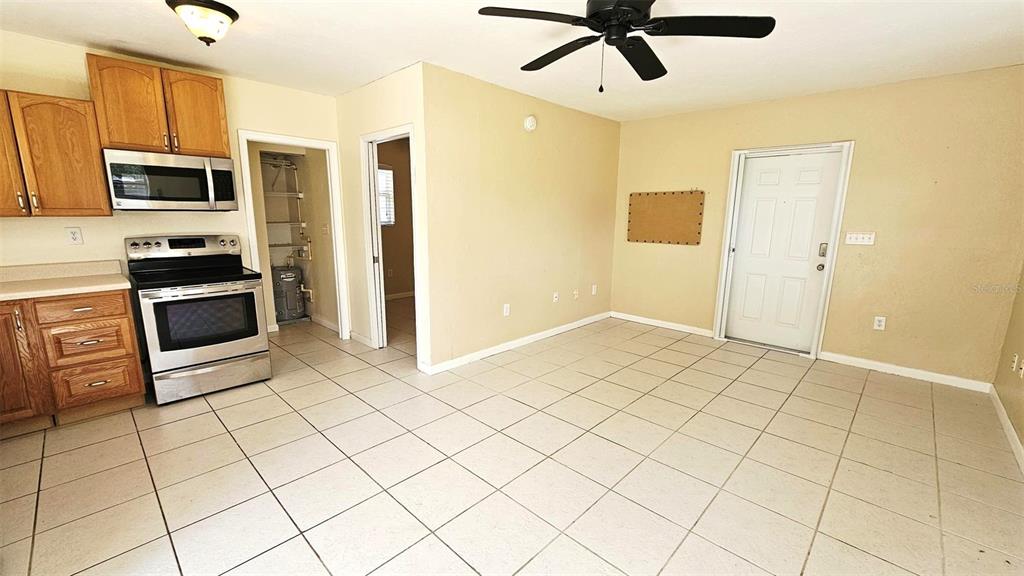 A kitchen with wood cabinets, stainless steel appliances, and tile flooring opens to a room — 865 PALM AVENUE UNIT A, ENGLEWOOD, FL