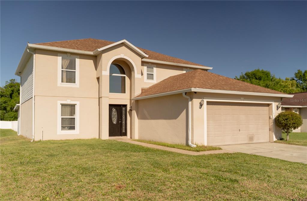 A two-story stucco house with a brown shingled roof and an attached two-car garage — 186 CEDAR RIDGE LANE, SANFORD, FL