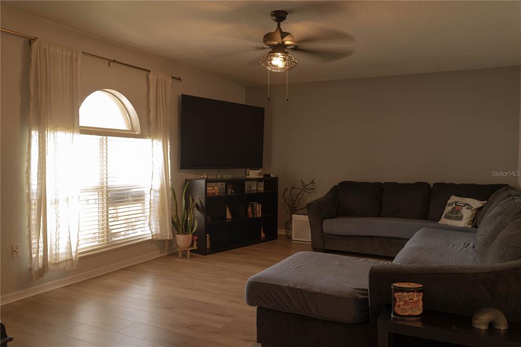 A living room features a large sectional sofa, a television on a shelf, and arched windows — 186 CEDAR RIDGE LANE, SANFORD, FL
