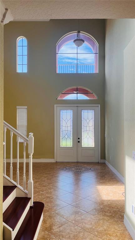 A two-story foyer features tile flooring, a staircase, and large arched windows above the door — 1221 DUMAINE AVENUE, PORT ORANGE, FL