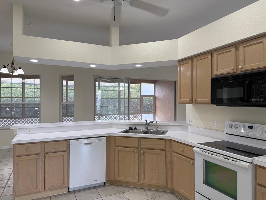 A kitchen features light wood cabinets, white countertops, a white dishwasher, and a white stove — 2805 HONEYWELL PLACE, LAKELAND, FL