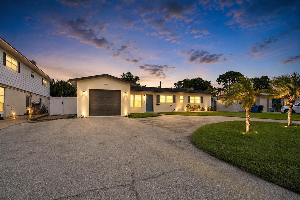 A single-story house with a garage and a large paved driveway at dusk — 6781 33RD AVENUE N, ST PETERSBURG, FL