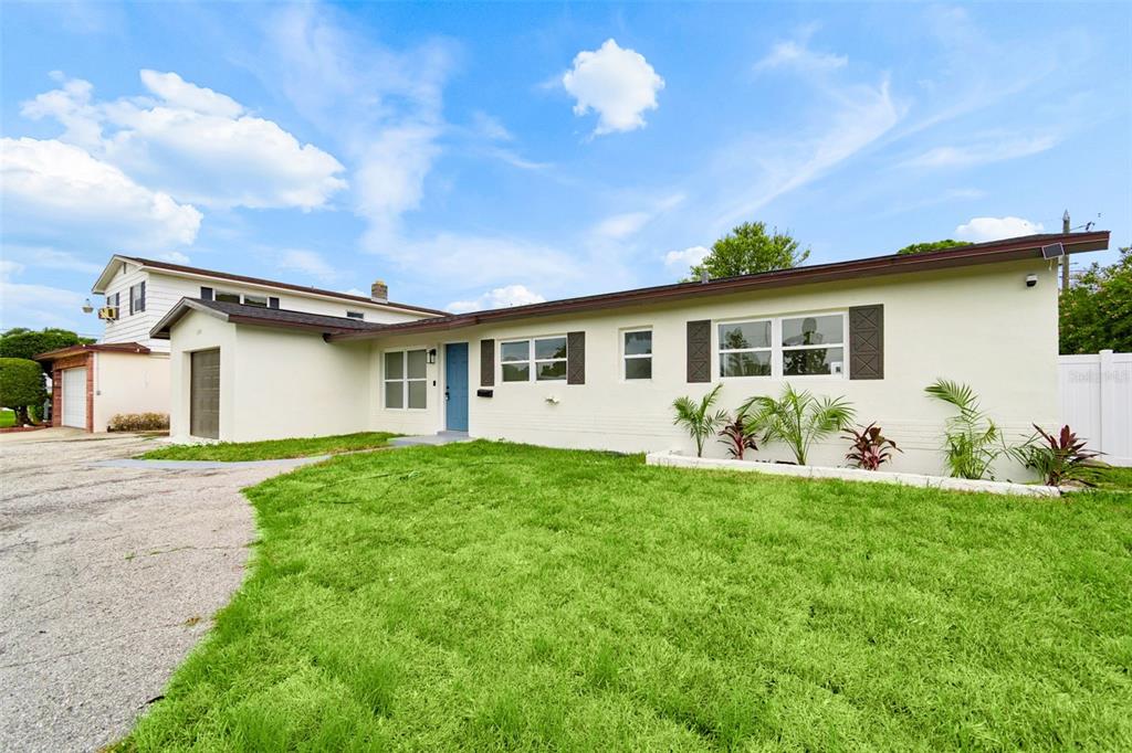 A single-story house with a light-colored exterior, a blue front door, and a gravel driveway — 6781 33RD AVENUE N, ST PETERSBURG, FL