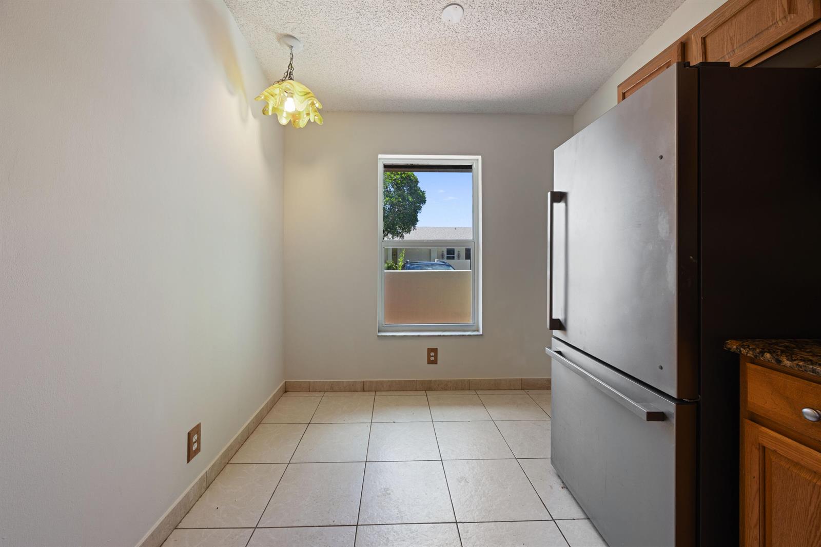 A bright living room features white tile floors, a crystal chandelier, and sliding glass doors — 5227 Copperleaf Circle, Delray Beach FL 33484, DELRAY BEACH, FL