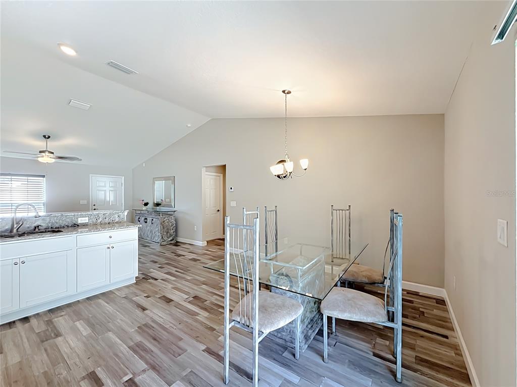 A dining area with a glass table, metal chairs, and wood-look flooring near a kitchen — 13244 49TH, OCALA, FL