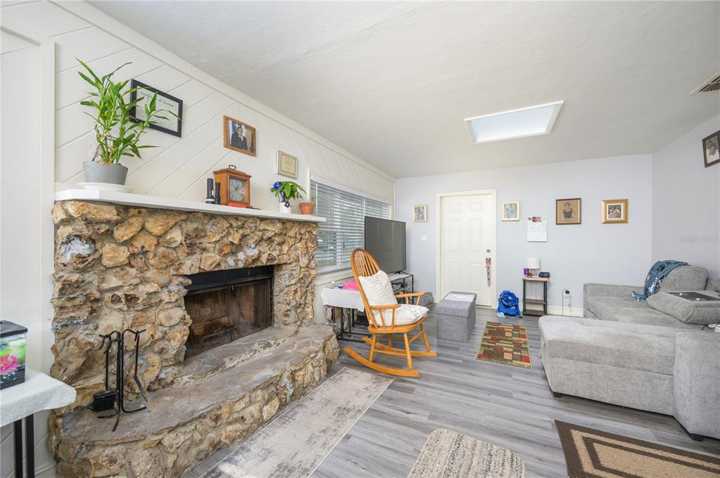 A living room features a stone fireplace, a rocking chair, and light gray flooring — 1006 SAN DOMINGO ROAD, ORLANDO, FL