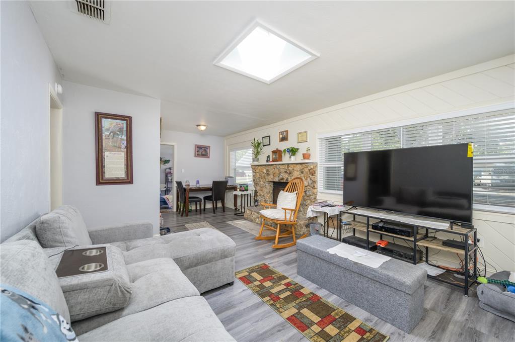 A living room features a stone fireplace, gray sectional sofa, television, and wood-look flooring — 1006 SAN DOMINGO ROAD, ORLANDO, FL
