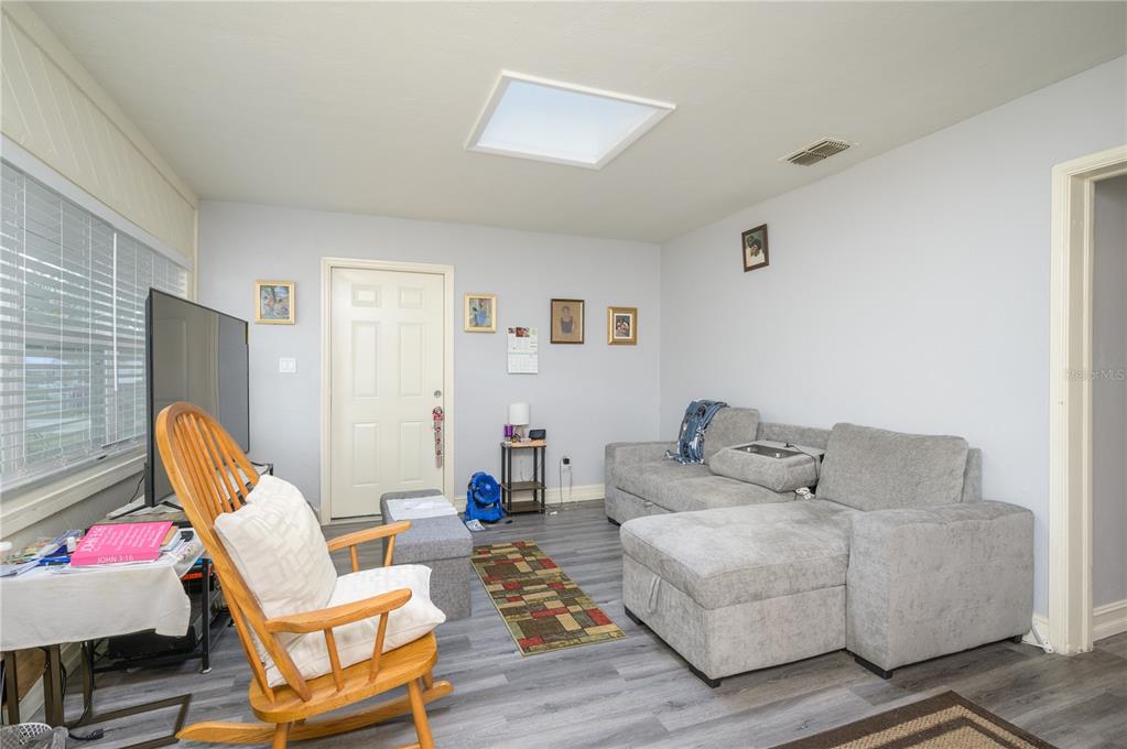 A living room features gray flooring, a sectional sofa, a rocking chair, and a skylight — 1006 SAN DOMINGO ROAD, ORLANDO, FL