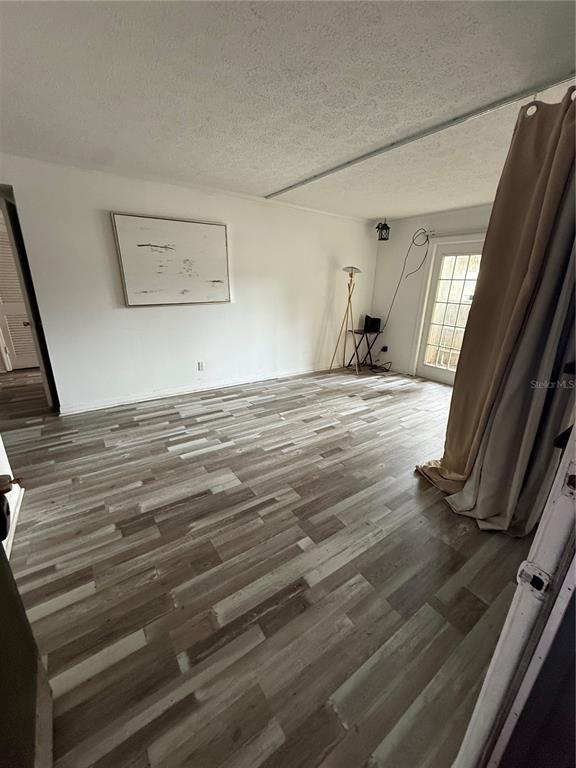 A room with light-colored walls, wood-look laminate flooring, a framed picture, and a sliding door — 305 WYMORE ROAD UNIT 100, ALTAMONTE SPRINGS, FL
