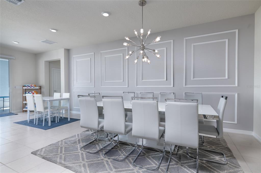 A dining room features a long white table, modern chairs, and wall molding — 3217 LILAC WAY, DAVENPORT, FL