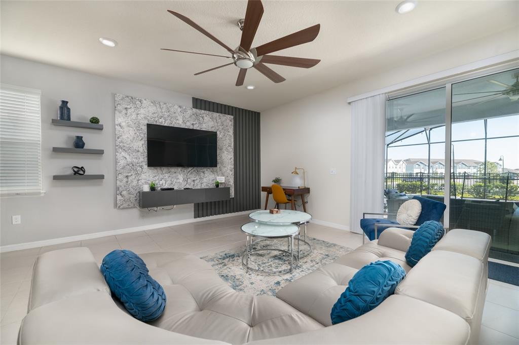 A living room features a large sectional sofa, a wall-mounted television, and a sliding glass door — 3217 LILAC WAY, DAVENPORT, FL