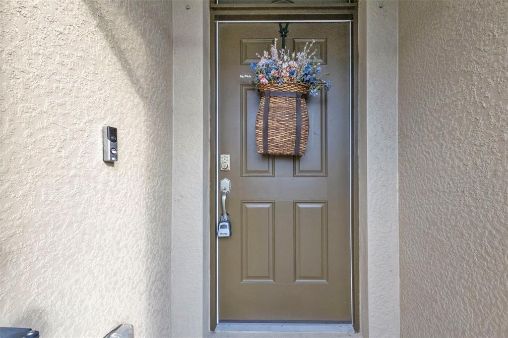 A brown front door with a floral basket wreath and a lockbox on the handle — 7676 MIKASA DRIVE, PUNTA GORDA, FL