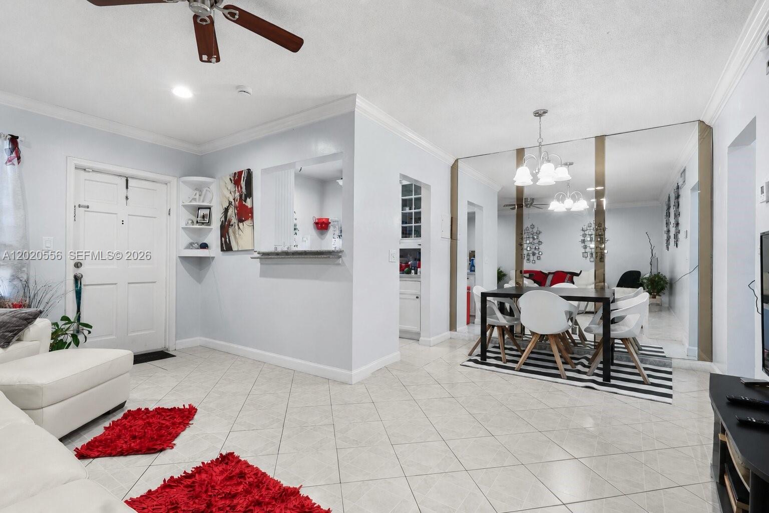 A living and dining area features white tile floors, a mirrored wall, and a ceiling fan — 2219 Polk St # 5A, Hollywood FL 33020, HOLLYWOOD, FL