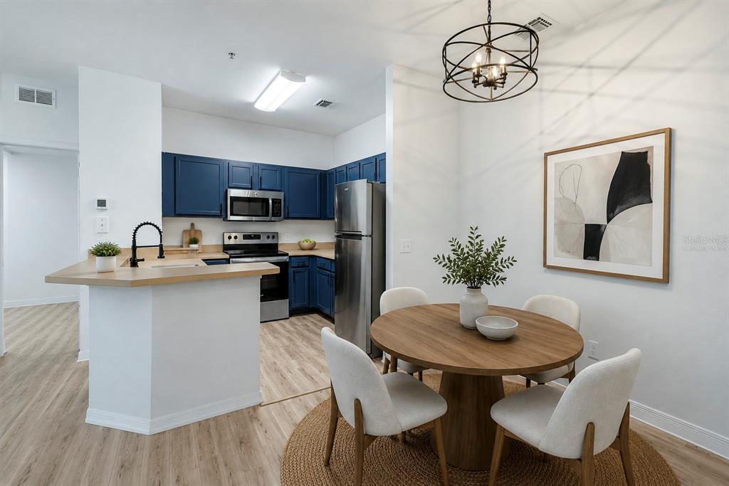A kitchen with blue cabinets and a breakfast bar next to a round dining table — 8225 CLAIRE ANN DRIVE UNIT 101, ORLANDO, FL