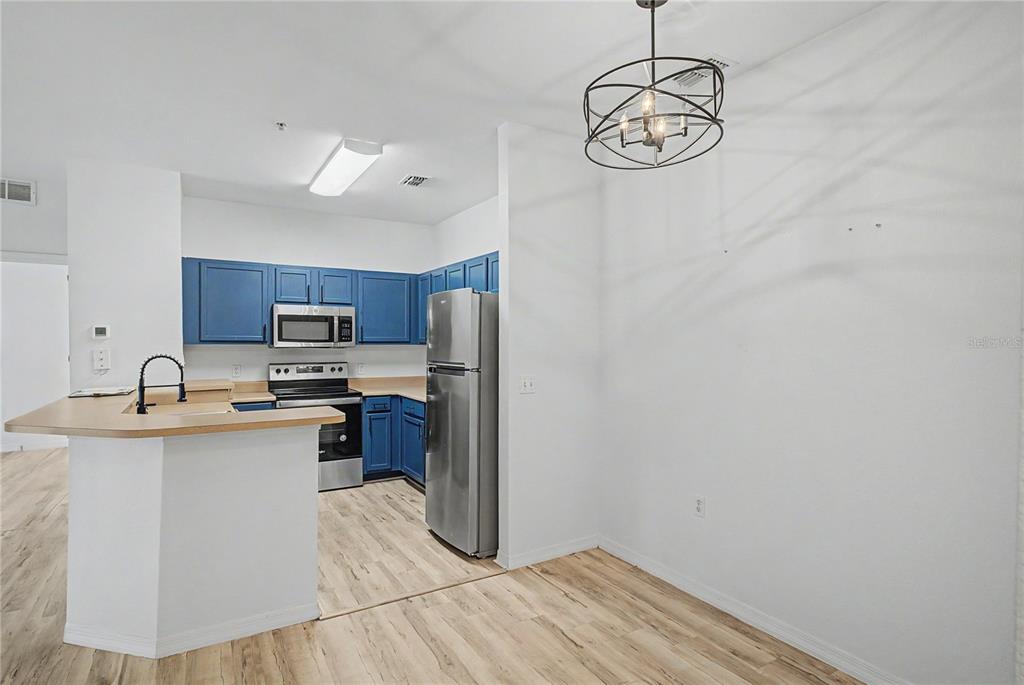 A kitchen with blue cabinets, stainless steel appliances, and a breakfast bar — 8225 CLAIRE ANN DRIVE UNIT 101, ORLANDO, FL