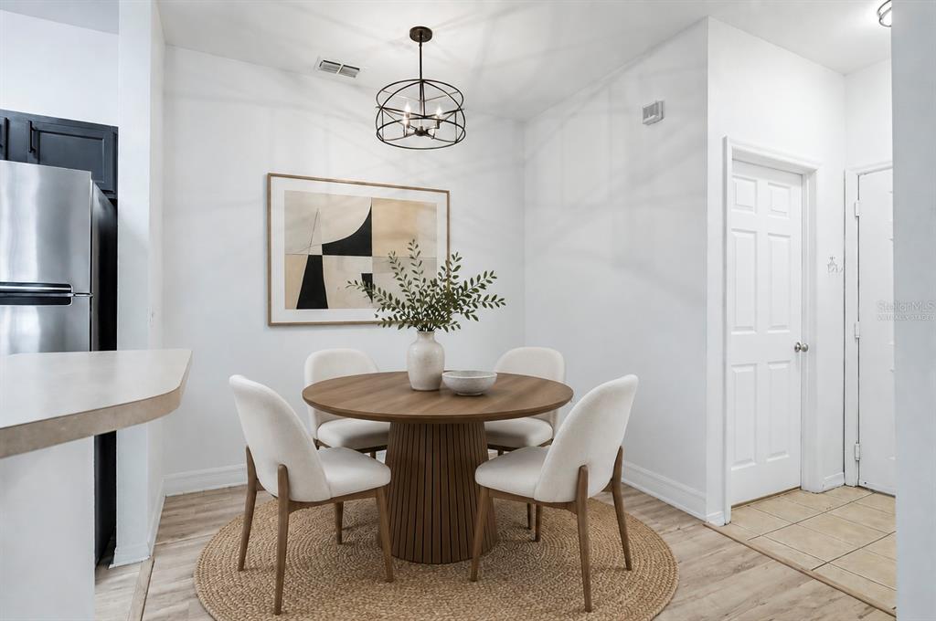 A dining area features a round wooden table, four cream chairs, and a modern chandelier — 8225 CLAIRE ANN DRIVE UNIT 101, ORLANDO, FL